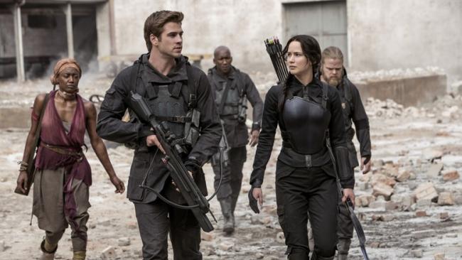 Mockingjay 2: Darsteller mit Gewehren in Trümmern